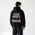 Model wearing a black Porsche-inspired typography hoodie with large cream lettering and a red hand-drawn crown back print