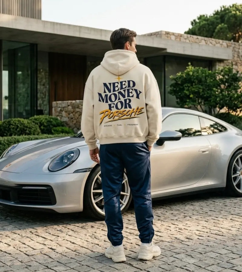 Model wearing a cream Porsche graphic hoodie from behind with curved navy NEED MONEY FOR typography and golden Porsche brush lettering
