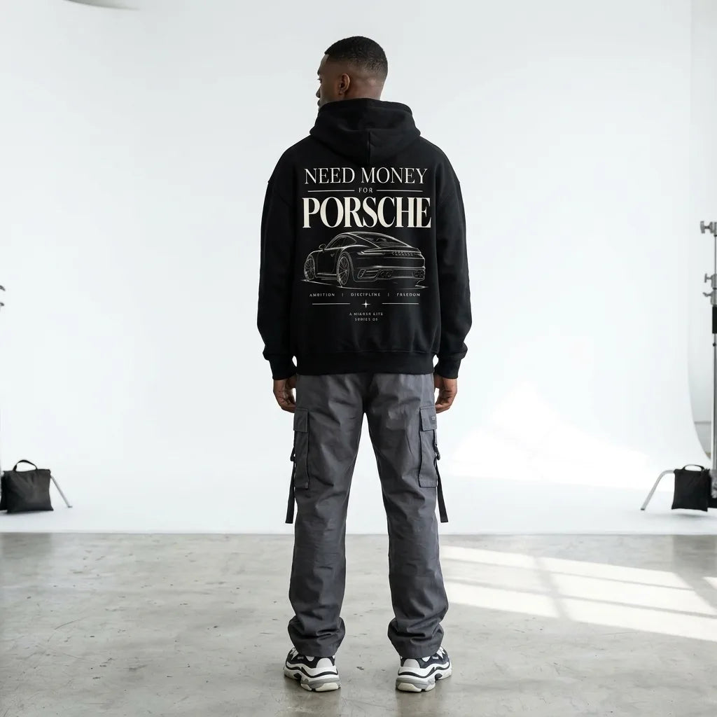 Model wearing black Need Money for Porsche hoodie with classic serif typography and detailed sports car line art on the back
