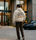Model wearing a cream Porsche graphic hoodie from behind with burgundy collegiate lettering and lavender handwritten Porsche design