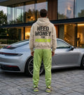 Model wearing a cream Porsche graphic hoodie from behind with oversized charcoal NEED MONEY FOR text and bright lime racing-style lettering