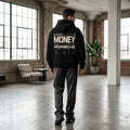 Model wearing black Porsche graphic hoodie with orange racing accents, bold MONEY lettering and Same Hustle Different Level back print