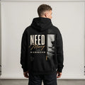 Model wearing a black Porsche graphic hoodie with cream NEED lettering, gold Money script and vertical automotive photo print